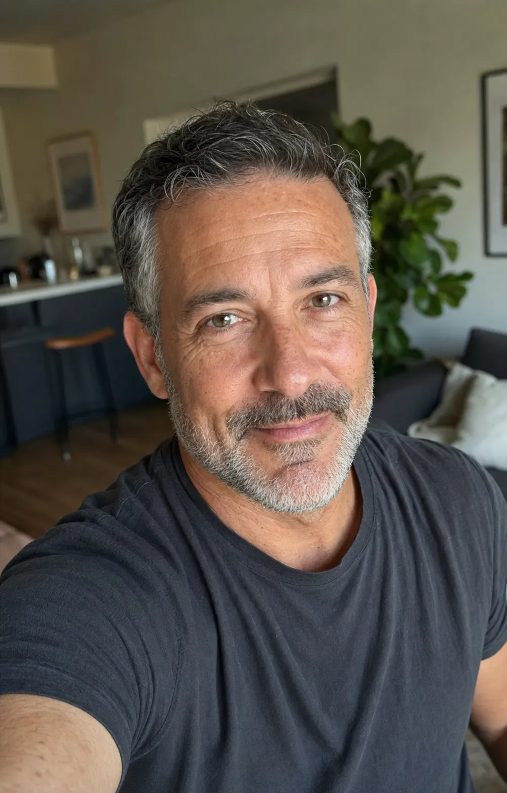 A 52-year-old man rendered with the aging-preservation rule line applied, showing genuinely half-grey salt-and-pepper hair, visible nasolabial lines, soft under-eye area, light expression lines around the eyes, and natural mid-50s skin texture — the actual face that walks into a cafe on date day, the rule-following state the article argues for.