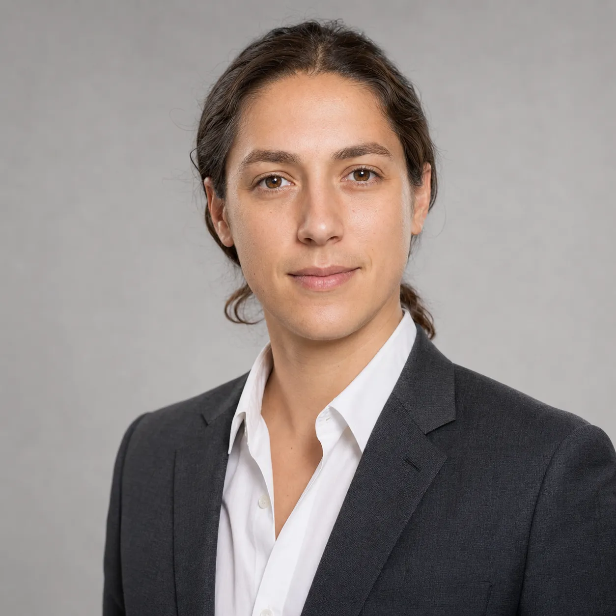 LinkedIn headshot example for a finance or consulting professional, charcoal suit jacket over crisp white open-collar shirt against a neutral mid-gray studio backdrop, soft balanced front-light, identity-locked 1:1 square recruiter-screen format.