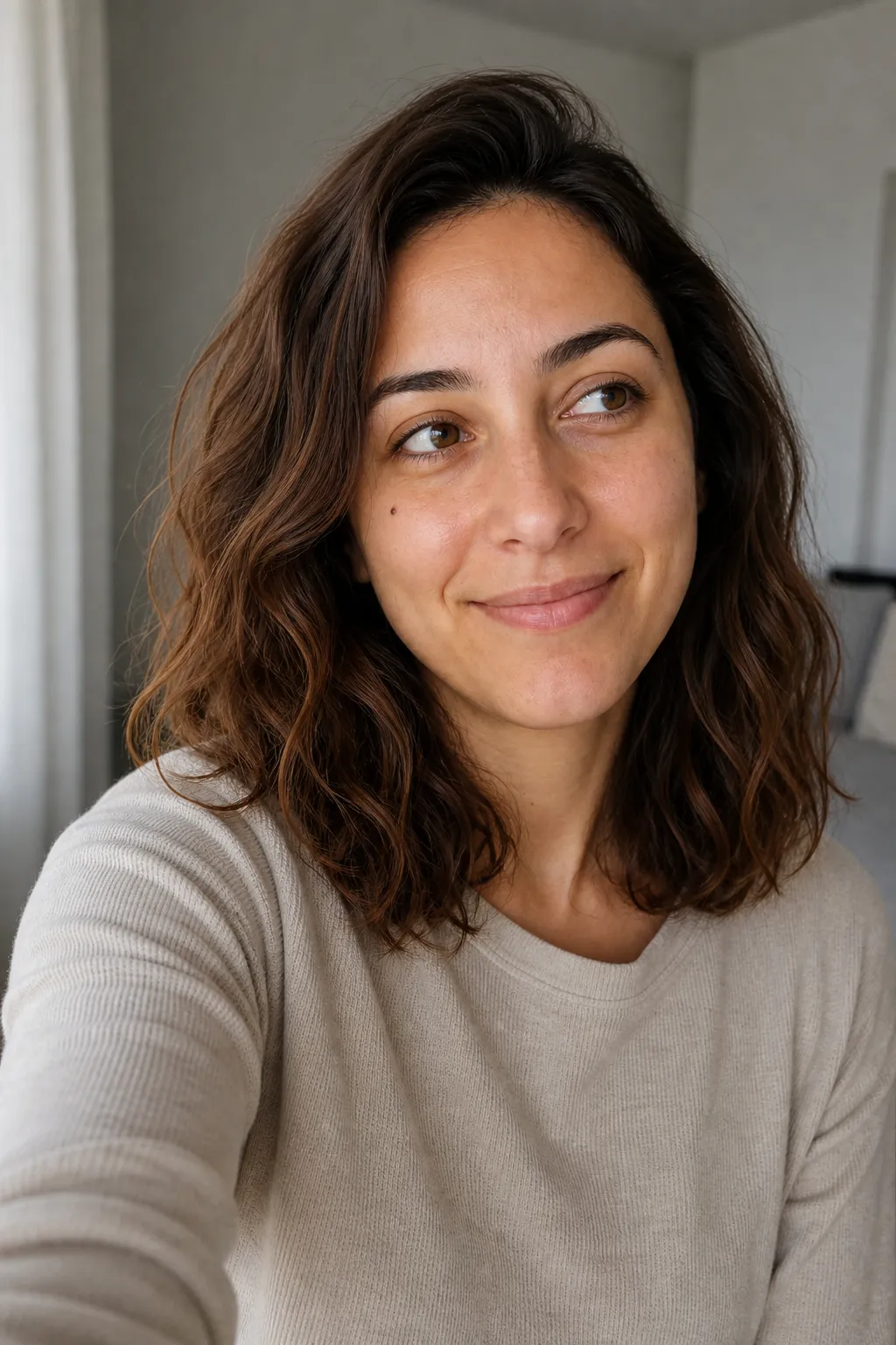 A woman taking a selfie while looking slightly off to the side instead of into the lens, a candid-feeling selfie angle.