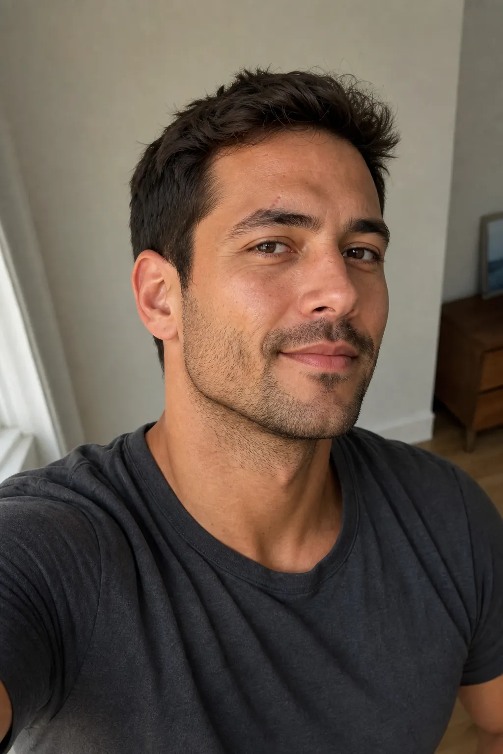 A man taking a selfie with the phone above eye level and his face turned three-quarters to show the jawline, with a relaxed expression.