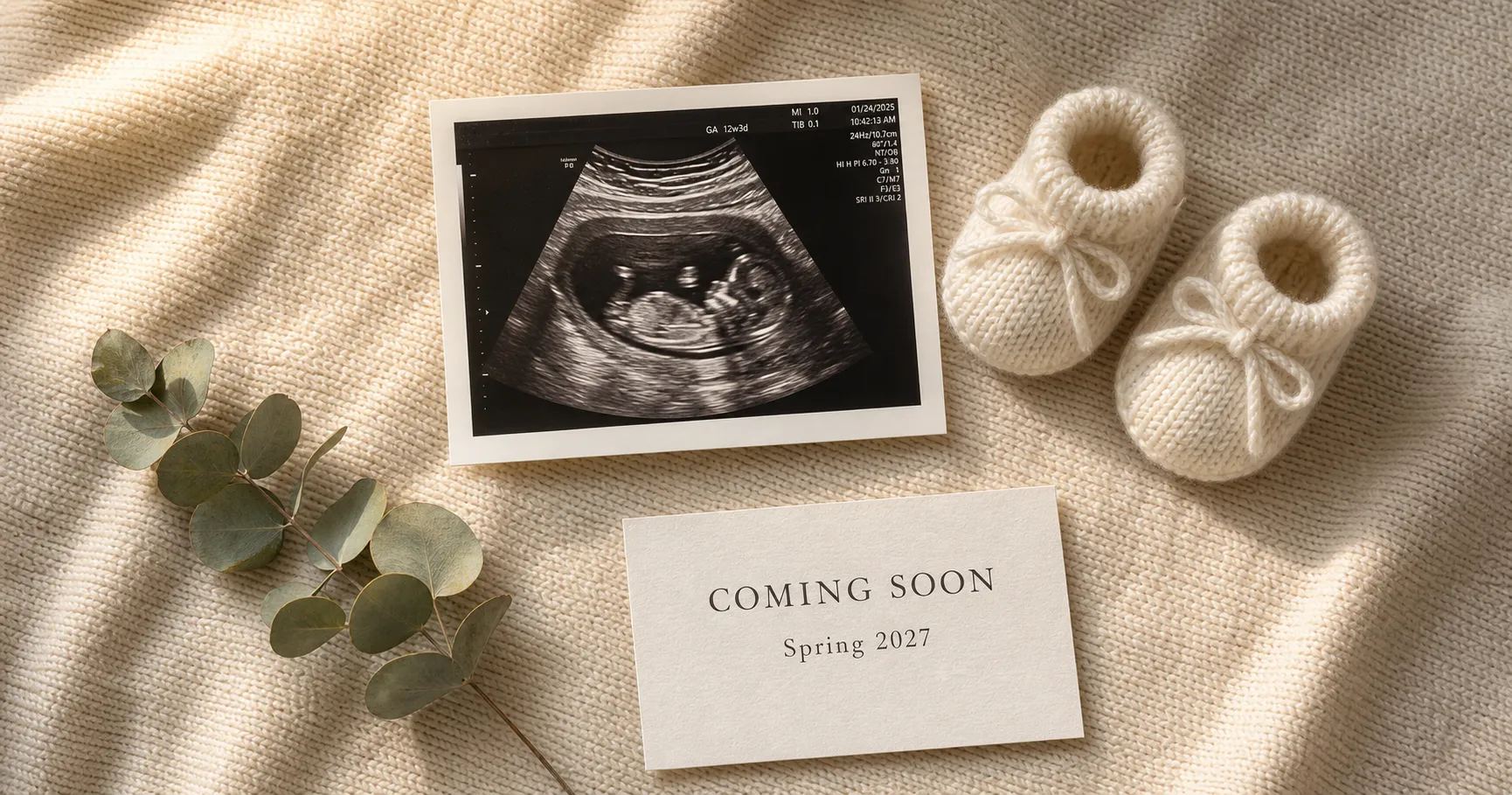 A polished overhead pregnancy announcement flat-lay with a sonogram, tiny booties, and a Coming Soon, Spring 2027 card on a cream knit blanket, ready to post.