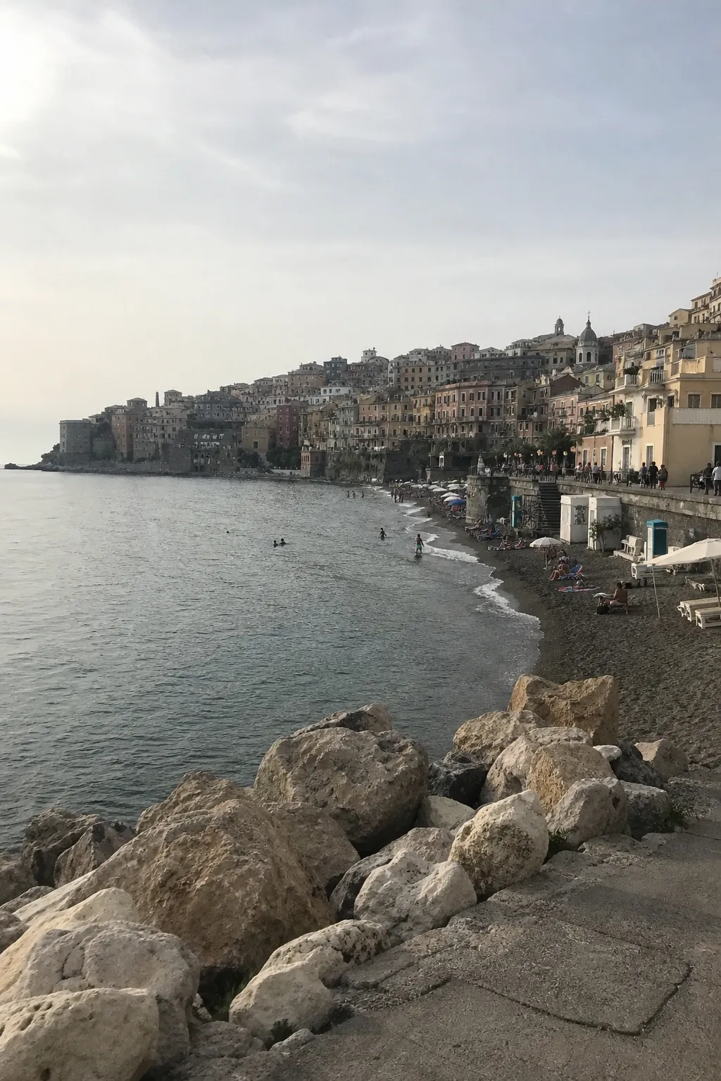 An ordinary dull vertical smartphone snapshot of a Mediterranean coastal town, the flat literal holiday photo most people start from before styling it.
