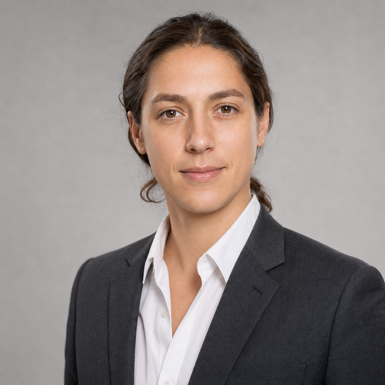 LinkedIn headshot example for a finance or consulting professional, charcoal suit jacket over crisp white open-collar shirt against a neutral mid-gray studio backdrop, soft balanced front-light, identity-locked 1:1 square recruiter-screen format.